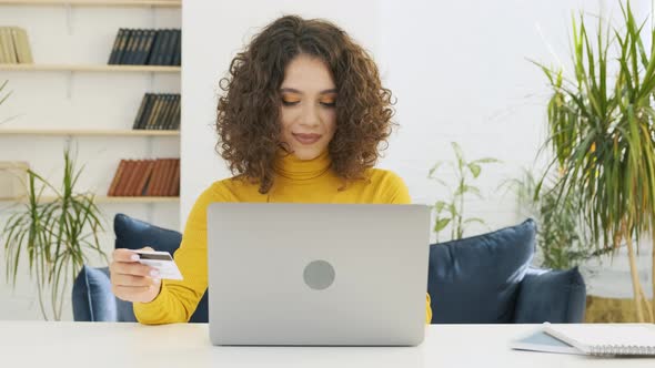 A Young Pretty Woman with Laptop Holding a Card Making Online Payment