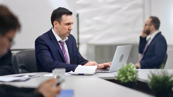 Busy Male Boss Working on Laptop Pc Surrounded By Colleagues at Modern Workplace