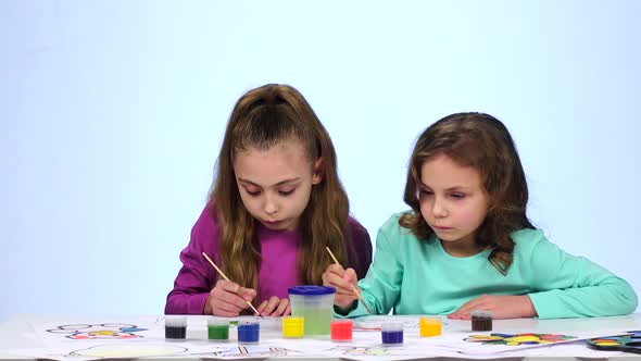 Children Paints a Picture, Dabs a Brush in a Glass with Water. Close Up. White Background. Time