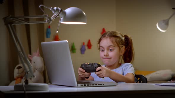 Cute Preschooler Girl Playing Video Games with Laptop and Controller