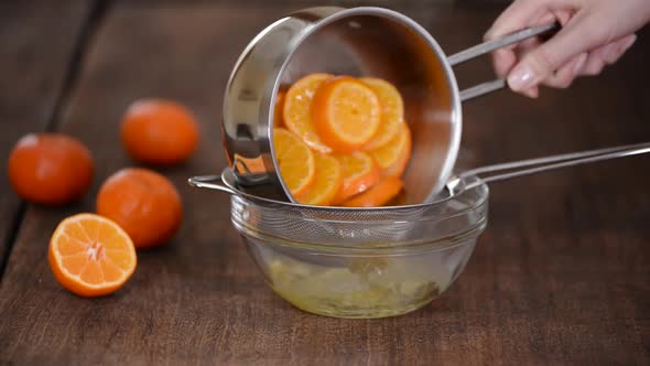 Woman Pouring the Tangerines Along with the Syrup Onto a Sieve