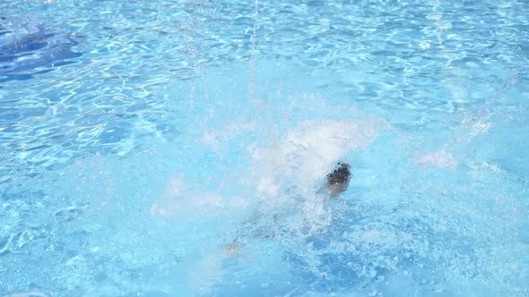 Caucasian boy jumping into the pool. Boy jumping in cool water of swimming pool