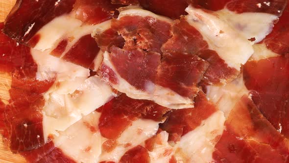 Fatty slices of serrano ham on a wooden board, close up view. Macro shot of high quality traditional