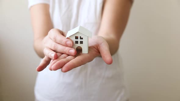 Woman Hand Holding Toy Model House Isolated on White Background