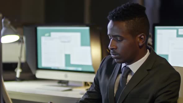 African Office Worker Typing on Computer at Night