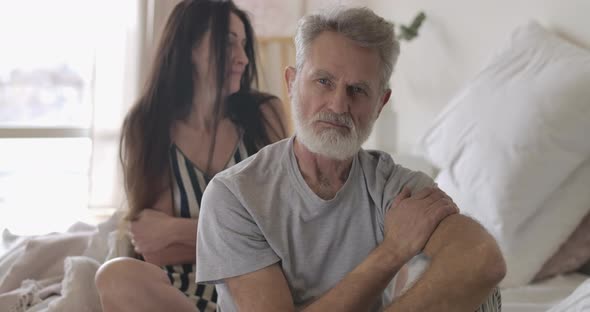 Close-up of Handsome Grey-haired Caucasian Man and Brunette Blurred Senior Woman Looking at Camera