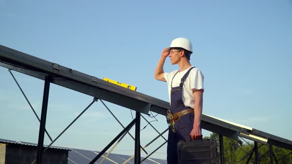 Young Enginneer Installing New Sunny Batteries. Worker in a Uniform and Hardhat Installing