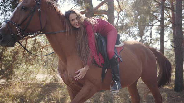 Young Happy Caucasian Female Equestrian Lying on Horseback and Caressing Her Pet