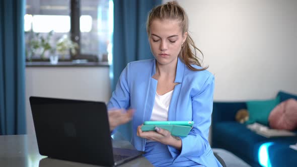 Front View Concentrated Caucasian Young Woman Messaging Online on Tablet Surfing Internet on Laptop