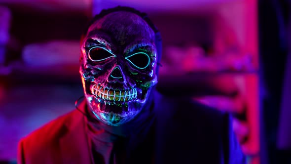 Gloomy Man with Face Mask of Scaring Skull in Nightclub in Halloween Night