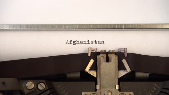 Typing word Afghanistan on retro typewriter. Close up.