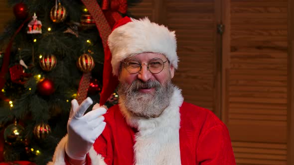 Portrait of Santa Claus Looking at the Camera Waves Hello and Makes Gesture Come Here