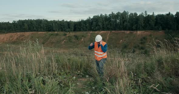 Working Engineer in a White Helmet Next to a Sand Pit