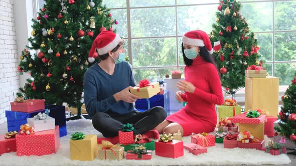 Caucasian man with hygiene mask give the present box to his couple for Christmas celebration