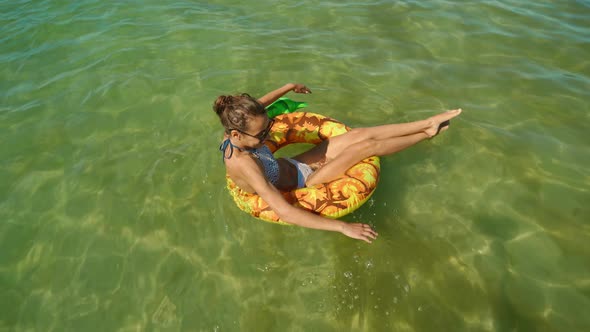 Top View Happy Smiling Young Woman in Sunglasses Swimming on Inflatable Pineapple Floating Ring in