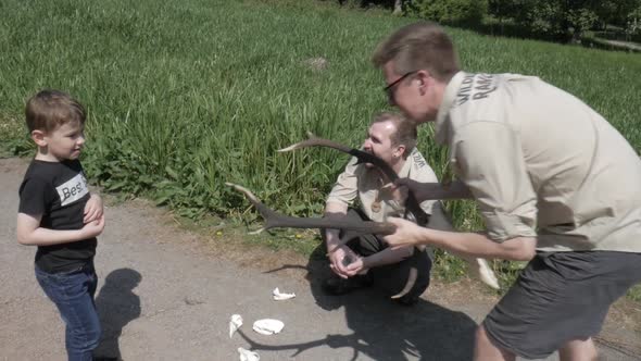 Two wilderness forest rangers show young child deer skull with antlers in SLOWMO