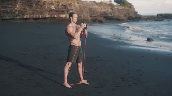 Side View of Tall Athletic Caucasian Man Doing Exercieses with Elastic Band