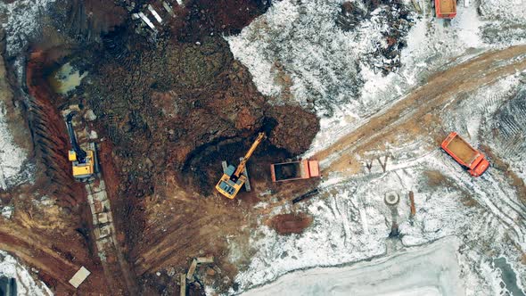 Aerial View From Above of a Construction Site with Excavators and Trucks Working.