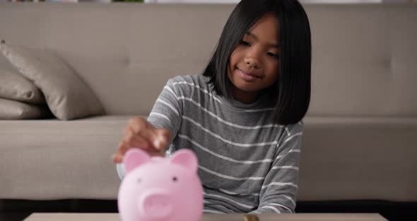 Girl putting coins into piggy bank