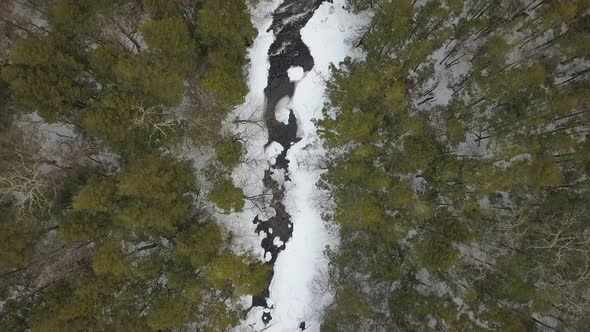 Top down drone shot of river in a winter wonderland