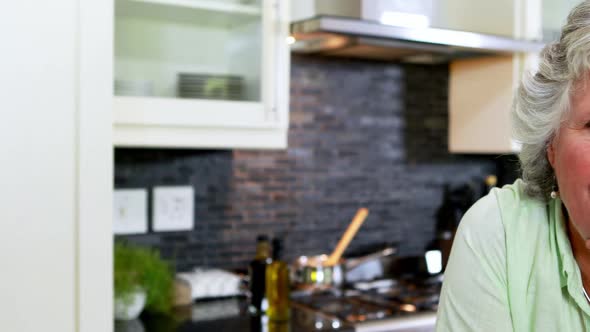 Happy senior woman sitting in kitchen 4k