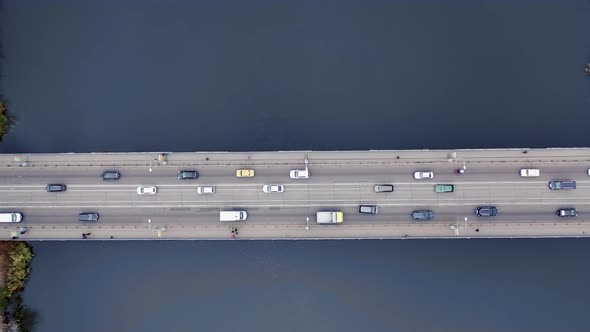 Pedestrians and cars move across the bridge in the city. Aerial view.