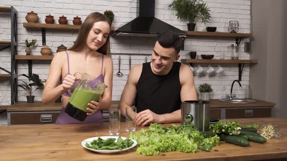 Making Green Juice at Home Young Fit Woman in Sportswear Pours Smoothie From a Blender Into a Glass