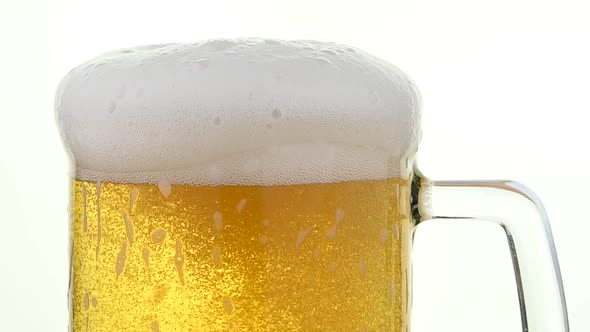 Close up pouring lager beer in glass over white