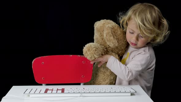 Small Girl with Teddy and Computer Keyboard
