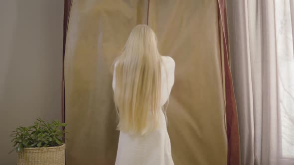 Back View of Little Caucasian Girl with Long Blond Hair Coming To Wardrobe and Opening It. Cheerful