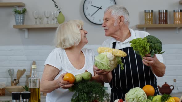 Senior Grandparents Couple in Kitchen. Mature Man and Woman Recommending Eating Raw Vegetable Food