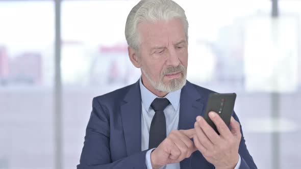 Old Businessman Celebrating Success on Smartphone