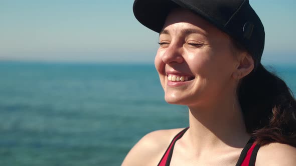 Closeup Portrait of Happy Young Woman in Black Cap Looking Away Closing Eyes Enjoying Sunny Day on