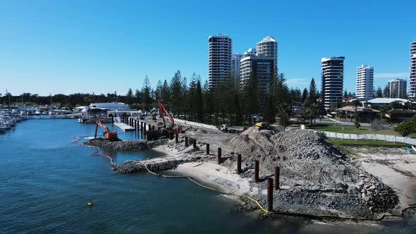 Large construction machinery working on the waters edge dredging and ring material to create a man-m