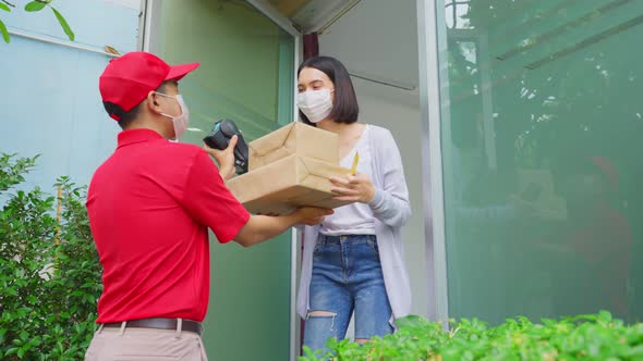 Asian deliver man wearing face mask in red uniform handling parcel box give to woman customer