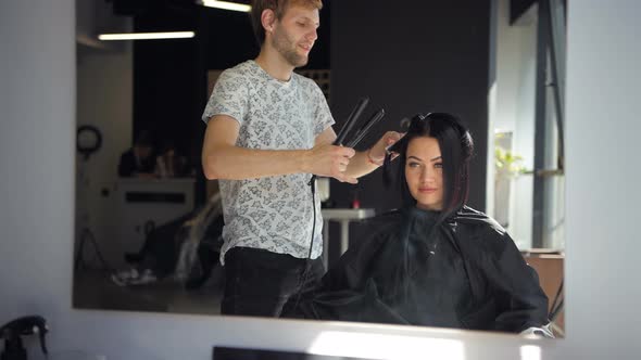 Hairdresser Straighten Brown Hair To Woman Using Hair Iron in Beauty Salon