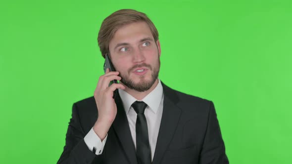 Young Businessman Talking Angry on Phone on Green Background
