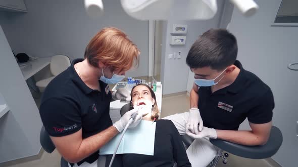 Stomatologist treating teeth. Female patient in the dental chair in modern clinic. 