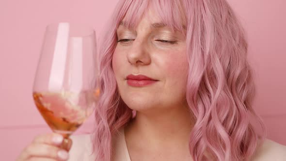 Beautiful Young Woman Drinking a Glass of Pink Wine Isolated Over Pink Background