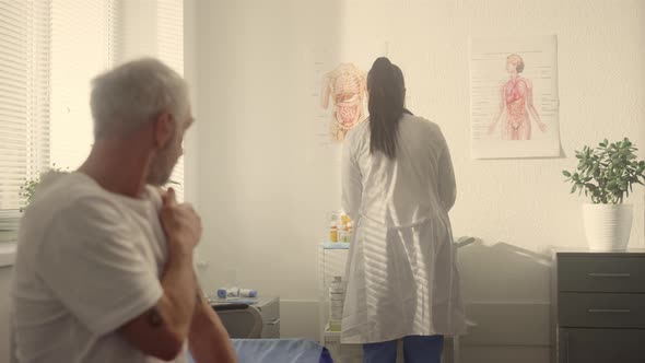 Elderly Man Holding Shoulder After Vaccine in Clinic Closeup