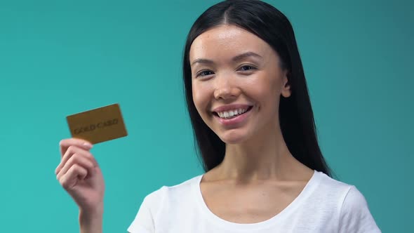 Cheerful Asian Lady Holding Golden Card, VIP Client of Luxury Boutique, Budget