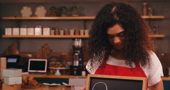 Smiling waitress showing slate with open sign