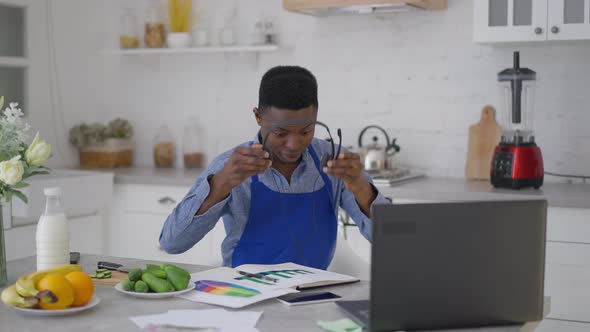 Young African American Male Manager Taking Off Earphones Closing Laptop and Sighing