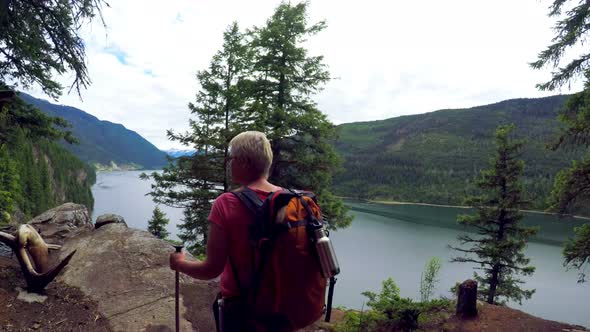 Mature woman with hiking pole standing at riverside 4k