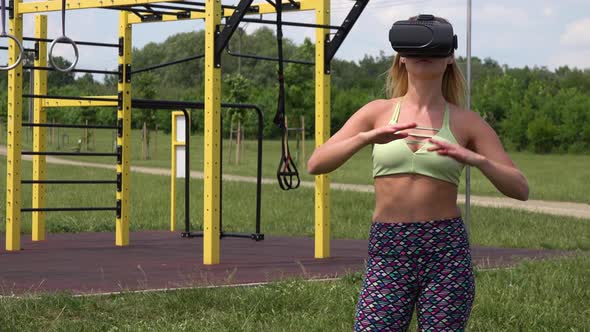 A Fit Woman with VR Glasses Warms Up at an Outdoor Gym