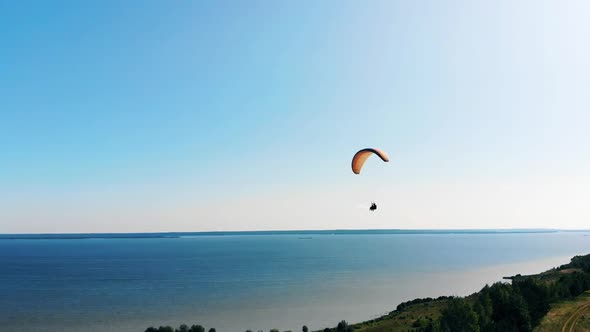 People Flying with a Paraglider and Wave Hands.