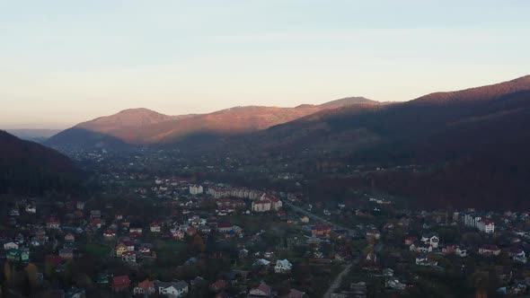 Aerial tilt-up footage of rural area in mountain valley at sunset.