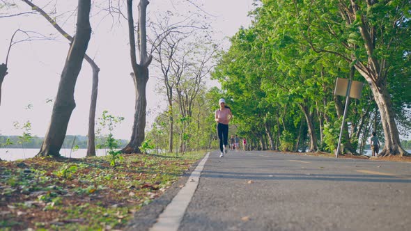 Asian young beautiful sport woman running on street in public park.