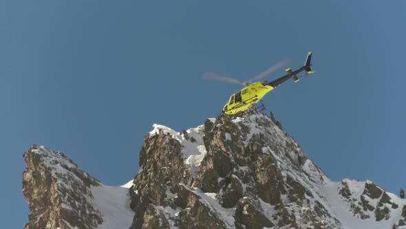 Rescue helicopter flying over a snowy mountain, during the Freeride Wolrd Tour competition, in Andor