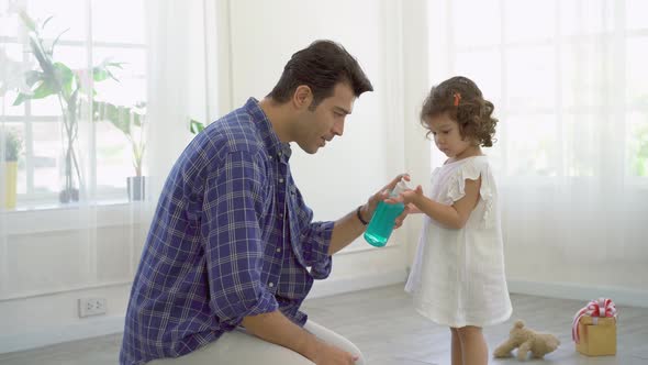 Father pouring alcohol hand wash gel to his daughter put on hand to protect her from coronavirus